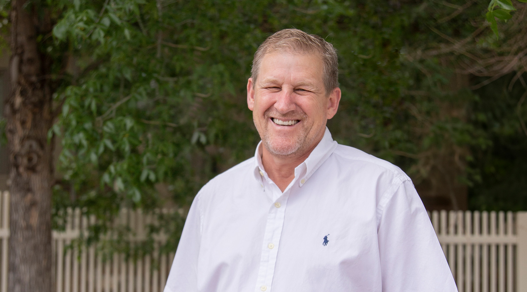 Wyo Dental Implants patient in a white shirt smiling outdoors in Casper
